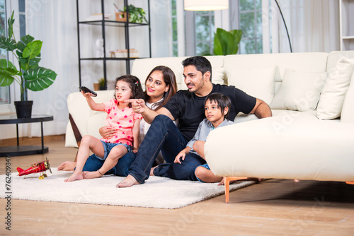 Indian family sitting on sofa looking at camera
