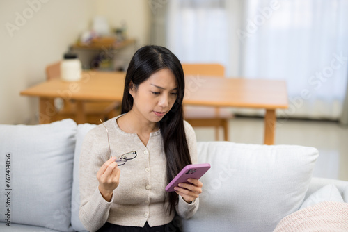 Woman suffering eyestrain trying to read on mobile phone at home