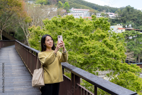 Tourist woman use mobile phone to take photo in the walking trail in the forest