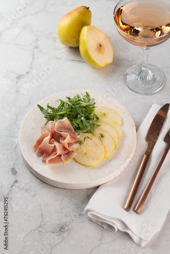 Fresh delicious salad with prosciutto, arugula with rose wine on light great marble background. Healthy diet concept. Italian cuisine. Vertical