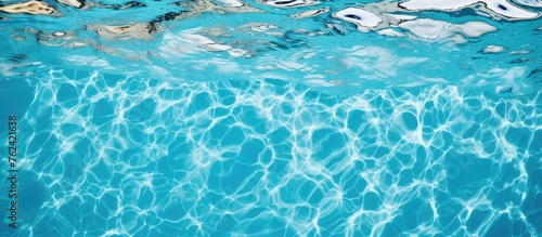 Close up of a swimming pool with a person gliding through the azure liquid, creating a mesmerizing pattern in the electric blue aqua