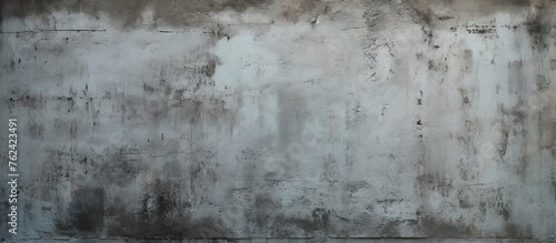 A close up of a weathered grey concrete wall with peeling paint, set against a freezing winter sky. The monochrome photography captures the natural landscape with frost and clouds photo