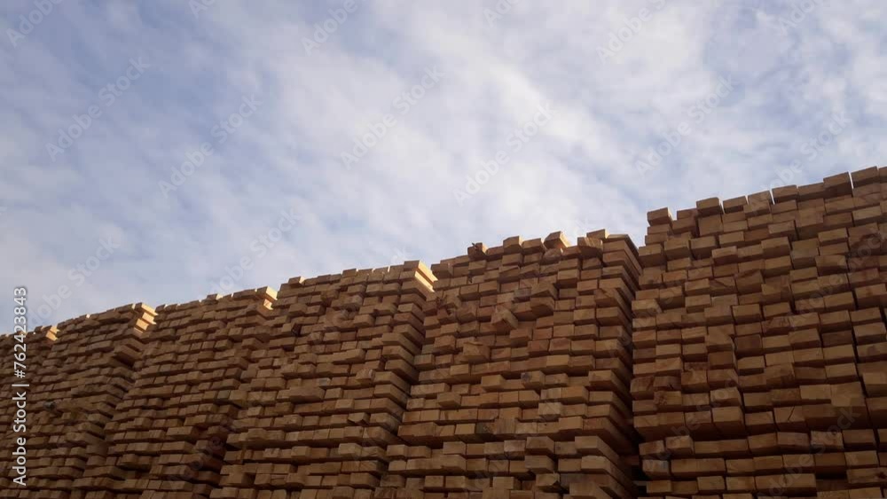 Stacked Timber Planks at a Lumberyard Awaiting Transportation. Stacked wooden planks in varying shades of brown at a timber storage facility. Stacked Timber Planks at a Lumberyard Awaiting Transportation. Stacked wooden planks in varying shades of brown at a timber storage facility.