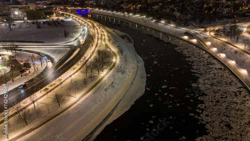 Drone photography of iced up river, footpath beside it and people walking during winter night photo