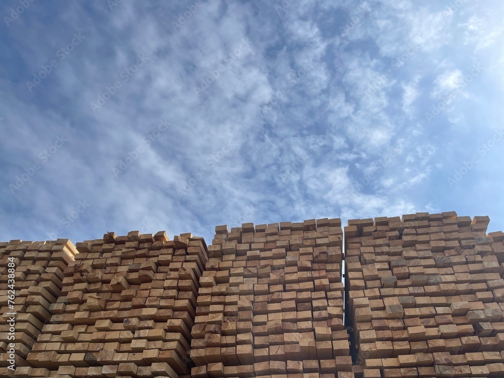 Stacked Timber Planks at a Lumberyard Awaiting Transportation. Stacked wooden planks in varying shades of brown at a timber storage facility. Stacked Timber Planks at a Lumberyard Awaiting Transportation. Stacked wooden planks in varying shades of brown at a timber storage facility.