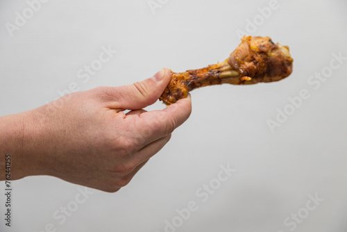 Fototapeta Naklejka Na Ścianę i Meble -  Caucasian man holds a crispy cooked a chicken leg