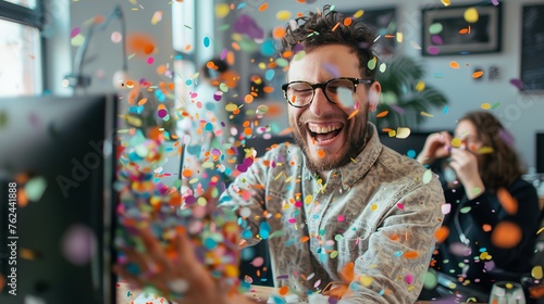 a happy guy in an office environment, sitting infront of a computer blowing confetti on his female collegue, Hasselblad X1D, Colors: Pastel, bright, nordic. photo