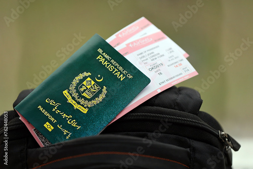 Green Islamic Republic of Pakistan passport with airline tickets on touristic backpack close up. Tourism and travel concept