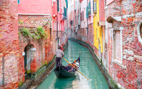 Venetian gondolier punting gondola through green canal waters of Venice Italy © muratart