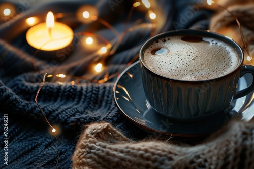 cup of coffee sits with lights and candle nearby