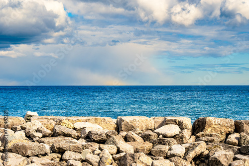 Photography marine background looking out over level rock across blue water to horizon with