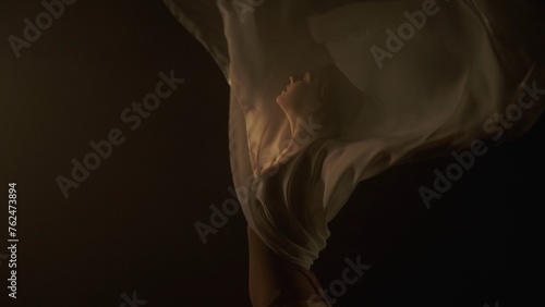 Young girl dancer in white chiffon on black background with emotional movements