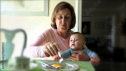 Grand-mother eating breakfast meal holding infant baby toddler grand-son