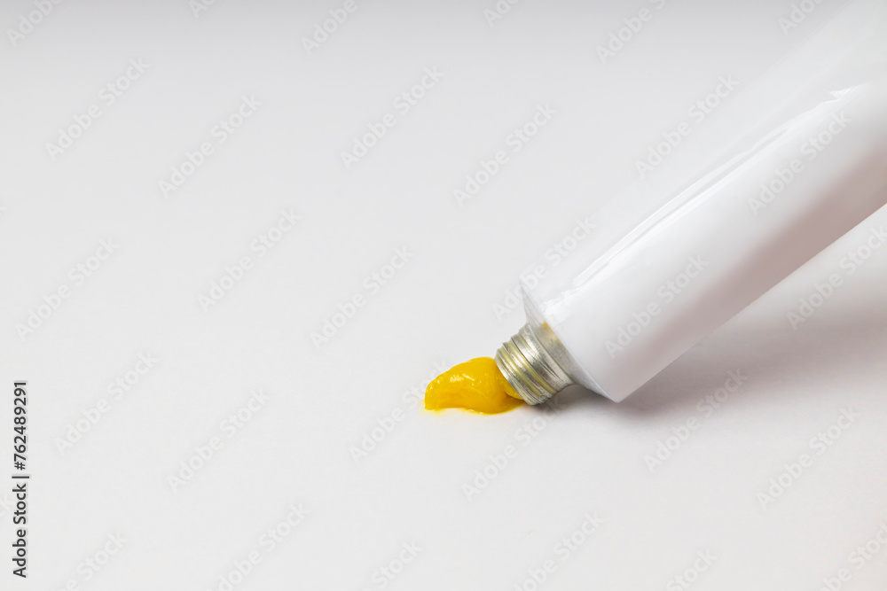 Opened ointment tube with yellow creme on the brigth background.Empty space Opened ointment tube with yellow creme on the brigth background.Empty space