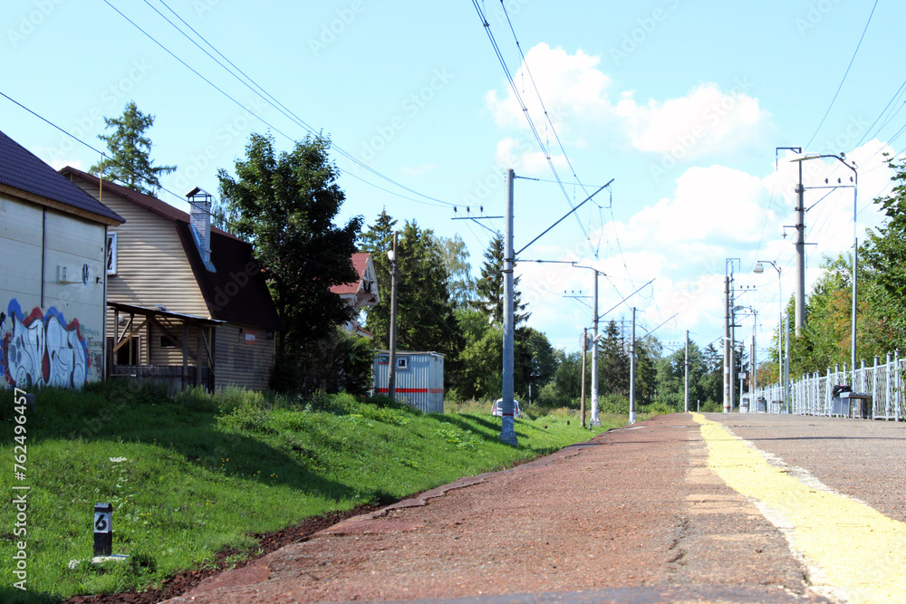 A small train station with no people. Sunny summer day.