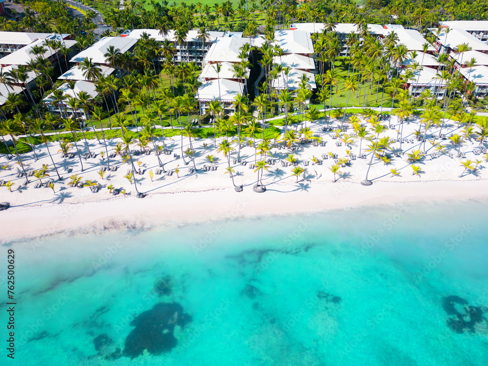 Aerial top view tropical hotel beach with white sand and palm trees. Turquoise water of the Caribbean sea. Best place for summer vacations