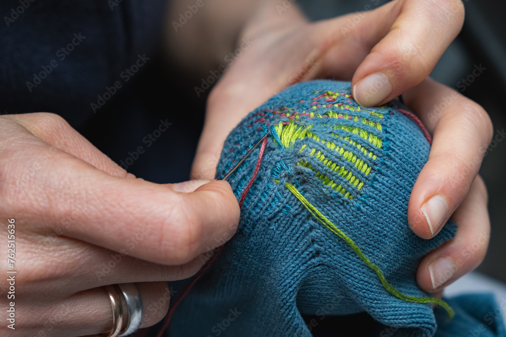 Mending clothes. Visible mending repairing sock. Darning old socks, reducing waste, slow fashion. Repair concept, selective focus. - obrazy, fototapety, plakaty 