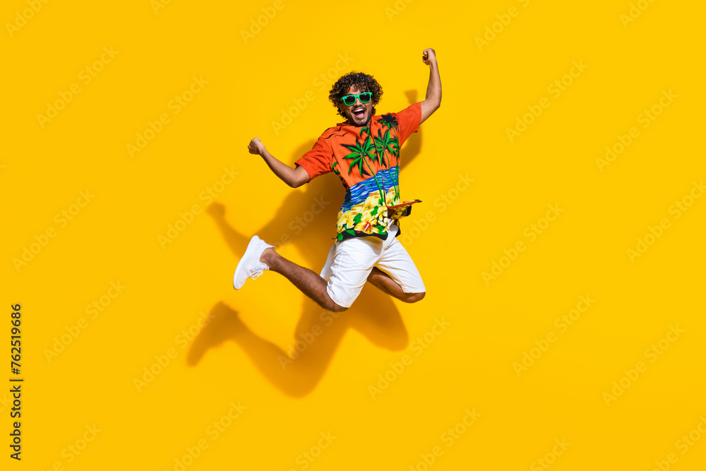 Full length photo of ecstatic guy wear hawaii shirt sneakers in glasses jumping shout yes win gambling isolated on yellow color background - obrazy, fototapety, plakaty 