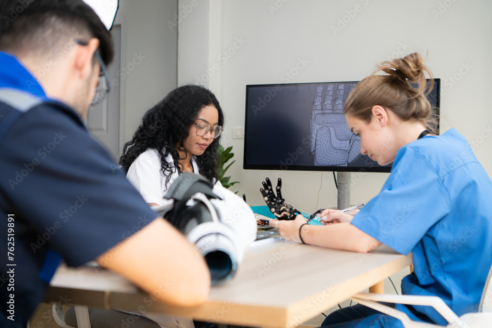 Obraz premium Engineers, doctors and physical therapists brainstorm ideas to design a robot with arm and hand organs, To be utilized for additional testing on patients.