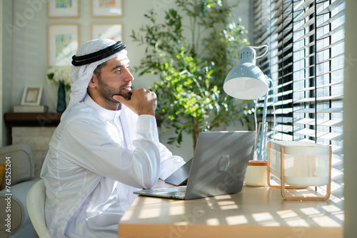 Portrait of young Arabic businessman working on laptop at home