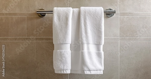 A Soft, Clean, White Towel Elegantly Draped on a Metal Rack in a Modern Bathroom with Beige Tiles