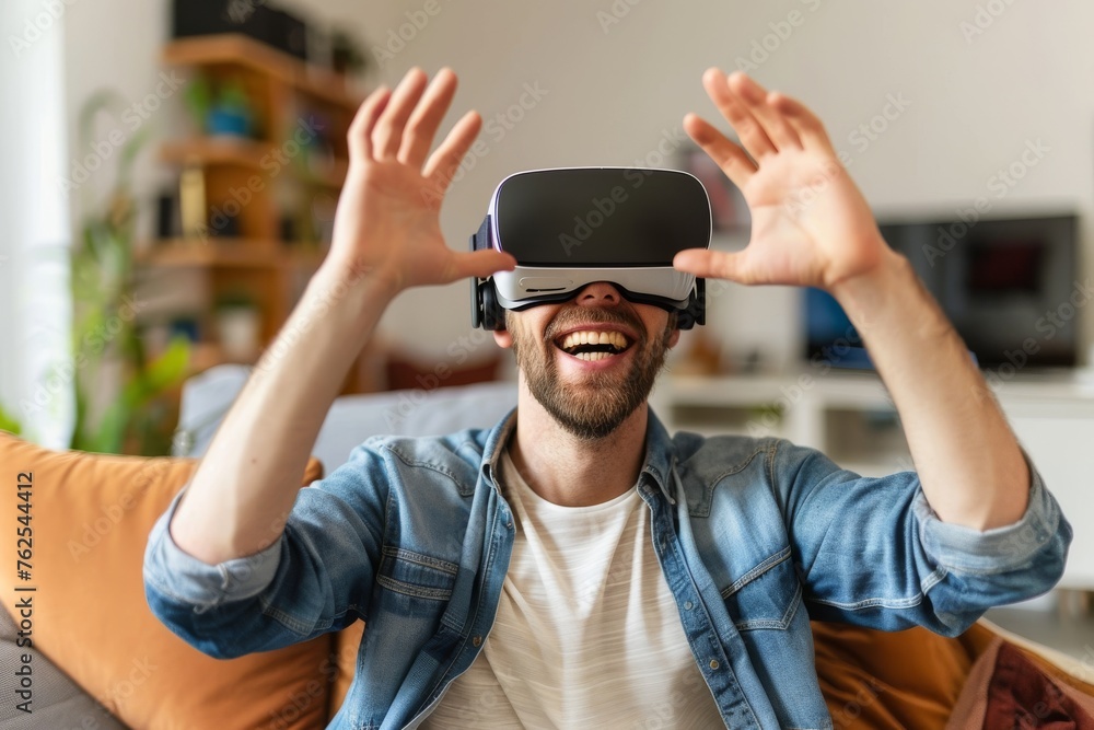 Happy man showing virtual reality glasses sitting on a sofa in the living room at home Happy man showing virtual reality glasses sitting on a sofa in the living room at home
