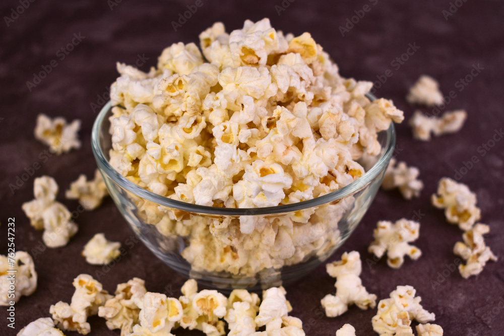 Popcorn in a glass transparent bowl on a dark background.
Popcorn in a glass transparent bowl on a dark background.
