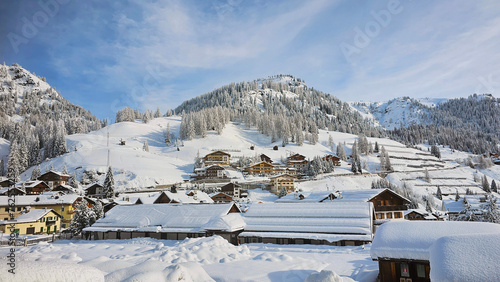 Beautiful winter view of village Arabba in Italy, province Belluno, after heavy snowfall. Slightly blue sky with snow covered houses, trees and mountains. 
