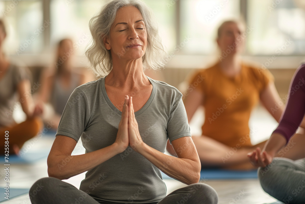 woman is doing yoga in a yoga class with other people in the background woman is doing yoga in a yoga class with other people in the background