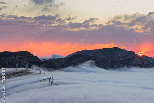 Wonderful sunset at the top of Picón Blanco in Espinosa de los Monteros, with a row of wind turbines at the top above a sea of ​​clouds