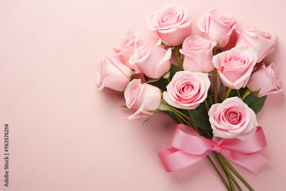 Bouquet of pink roses is arranged in pink ribbon. Roses are of various sizes and are placed in vase. Scene is one of love and romance, as roses are often associated with these emotions