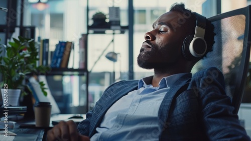 business, technology and people concept - happy african american businessman with headphones and computer listening to music at office photo