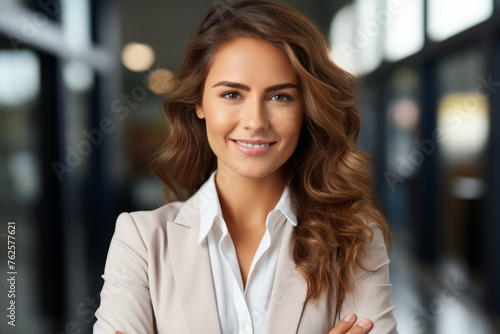 Woman with long brown hair and white shirt is smiling for camera. She is wearing suit and she is confident and professional