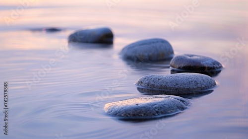 A collection of smooth river rocks arranged in a balanced composition, highlighted by the gentle ripples of clear water, under the soft glow of twilight.