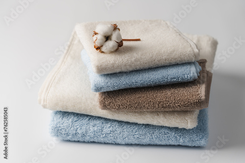 Stack of delicate colored cotton towels with cotton buds on white background