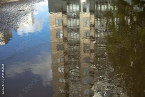 Reflection of building in puddle. Puddle in city. Reflection of house in water.