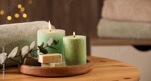 Spa composition. Burning candles  soap  towel and eucalyptus branch on wooden table  space for text
