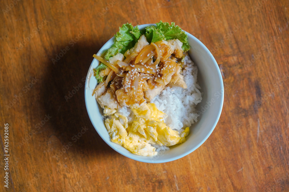 Chicken karage rice and teriyaki sauce sprinkled with sesame seeds on food packaging on a wooden table background Chicken karage rice and teriyaki sauce sprinkled with sesame seeds on food packaging on a wooden table background