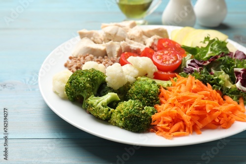 Balanced diet and healthy foods. Plate with different delicious products on blue wooden table, closeup