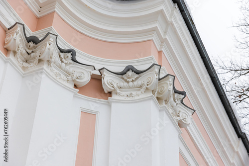 Classical portico with pink and white details under bright sky