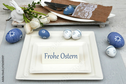 Osterkarte: Gedeckter Ostertisch mit Ostereiern, Teller,  Besteck und dem Text Frohe Ostern auf einer Platzkarte.