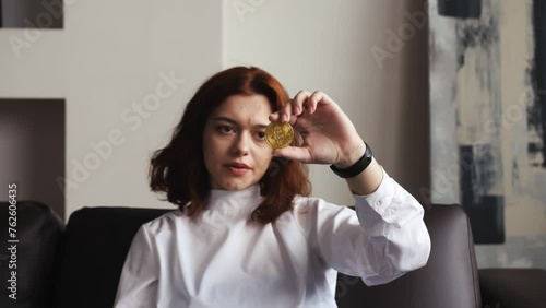 Dissatisfied sad woman showing gold bitcoin and throwing it away, downgrade of electronic currency. Indoor home or modern office. bad investition, money loss, crysis concept photo