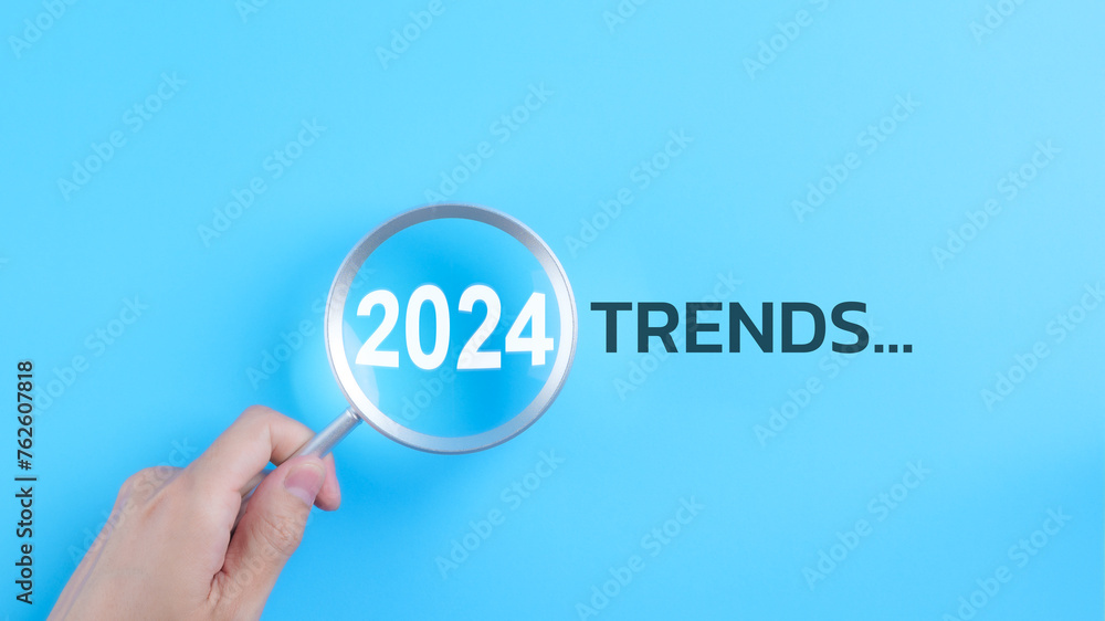 Trends 2024 year concept. Hand holding magnifying glass with 2024 trend searching bar for optimization 2024 business marketing trends and business plan in new year. Find information and new ideas. - obrazy, fototapety, plakaty 