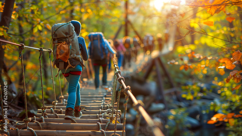 Group of hikers with backpacks walking across a suspension bridge surrounded by autumn foliage