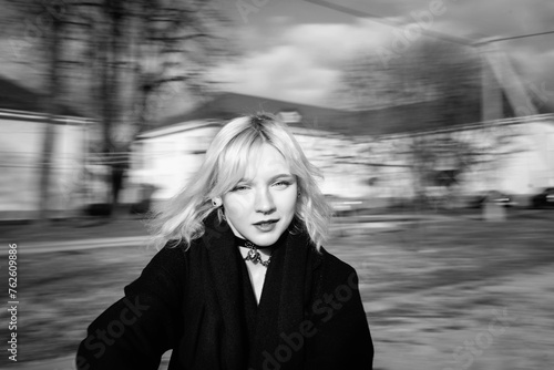 Portrait of a young beautiful blonde girl in a black coat. Black and white photo.