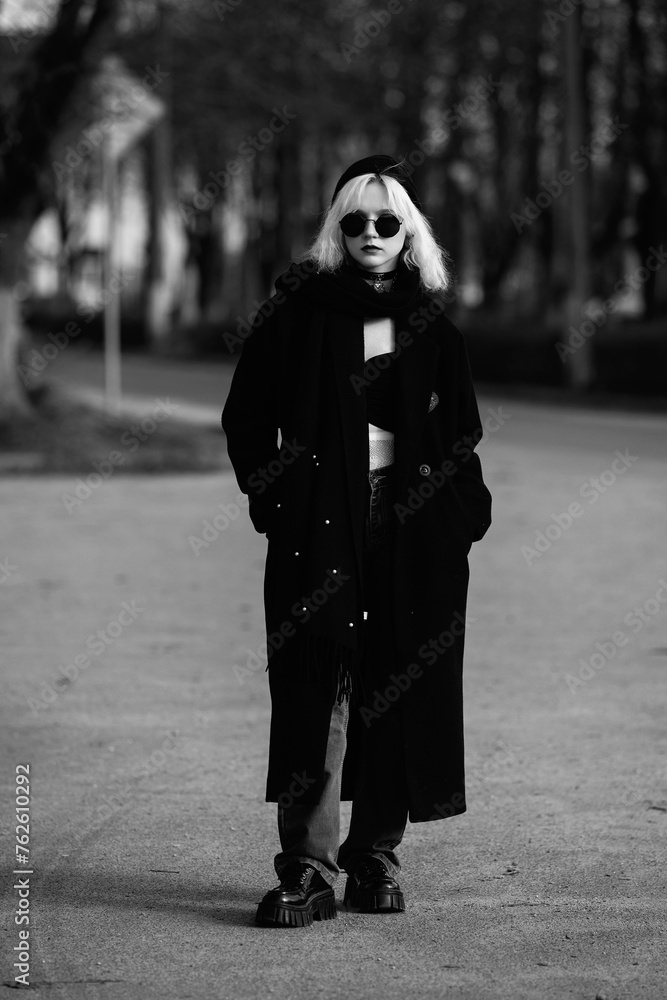 Portrait of a young beautiful blonde girl in a black coat. Black and white photo. Portrait of a young beautiful blonde girl in a black coat. Black and white photo.