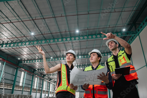 Three construction workers are standing in a large building