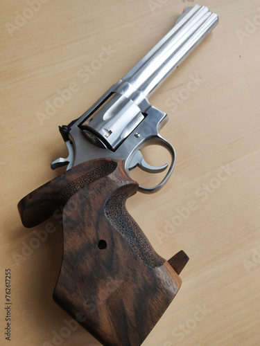 Rear view of a revolver-type pistol with anatomical grip on a wooden table
