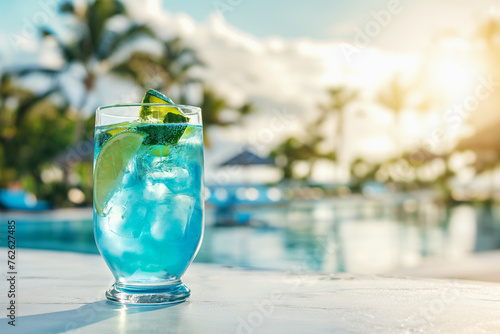Blue lagoon cocktail in a glass on a white concrete surface against the background of a luxury tropical hotel