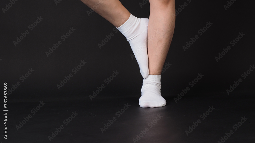 Fototapeta premium Legs wear white sock on black background.